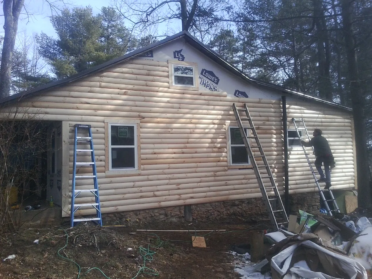 Ladders set against fresh log siding during an exterior remodel in Odessa